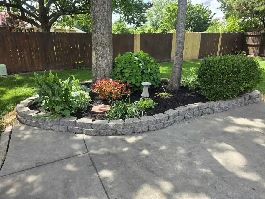 Planting bed with a stone border under mature trees
