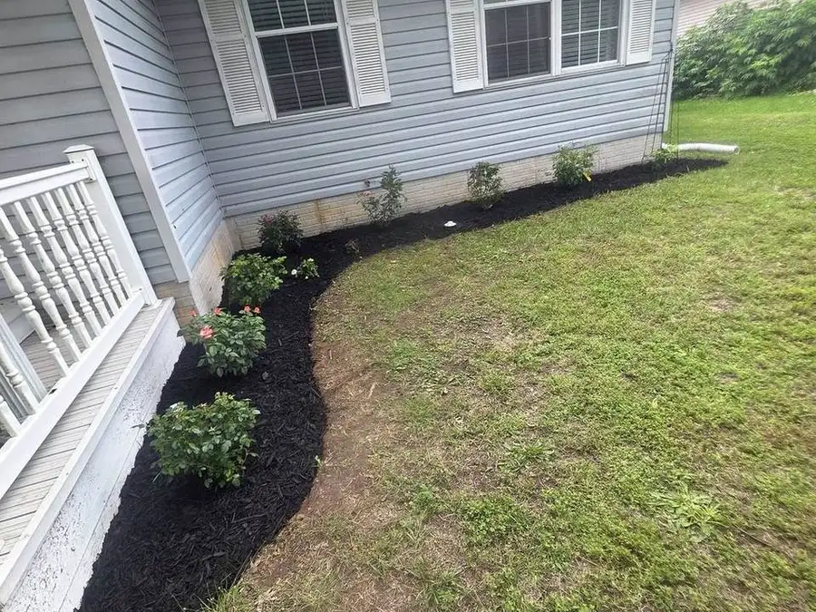 Stone border and mulch bed along a white house
